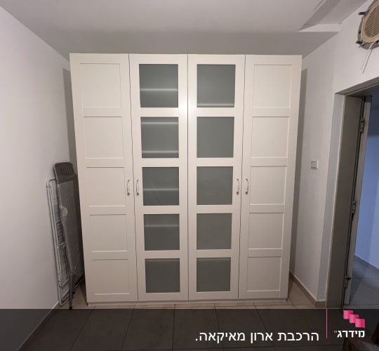 ארון בגדים לבן עם דלתות זכוכית בחדר